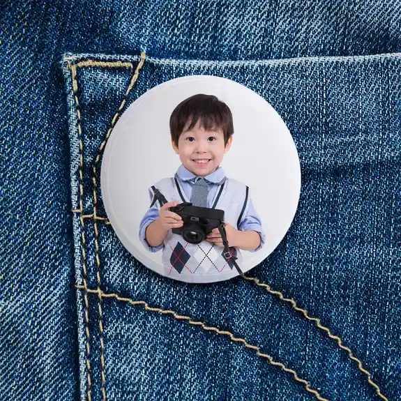 Photo button pin of smiling boy on denim