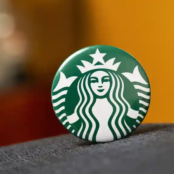 Green Starbucks logo button on gray fabric surface