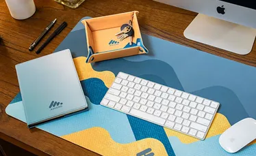 Home office desk with a printed mouse pad and notebook.