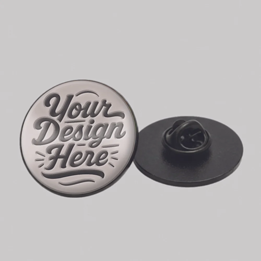 A round silver hard enamel pin reading "Your Design Here" with a polished, flat finish.